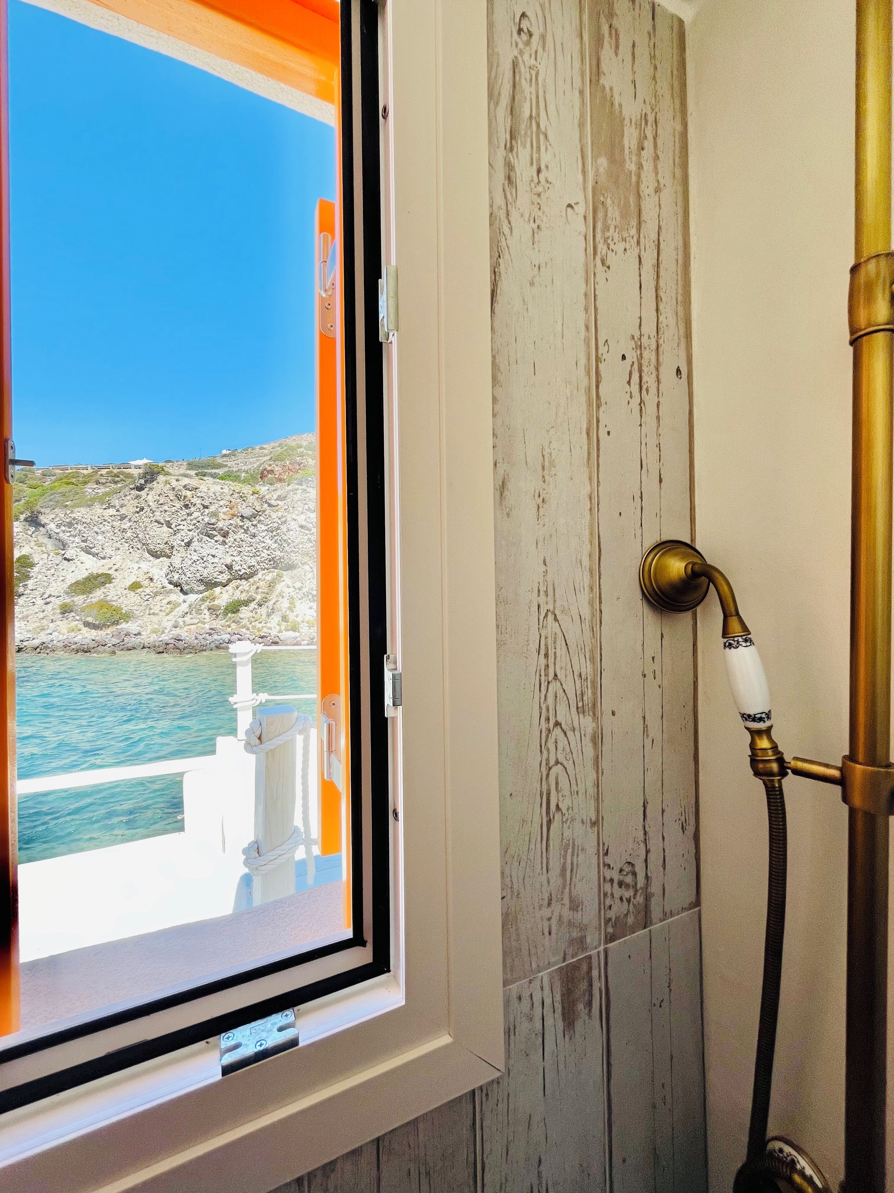 Ein Badezimmer mit einem Fenster mit Blick auf eine felsige Küstenlinie.
