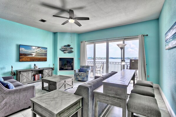 A spacious living room with a large window, a ceiling fan, and a view of the city.