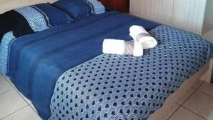 A bed with a blue patterned bedspread, a wooden headboard, and two pillows. - 4-bedroom house for 10 people (L'Étang-Salé)
