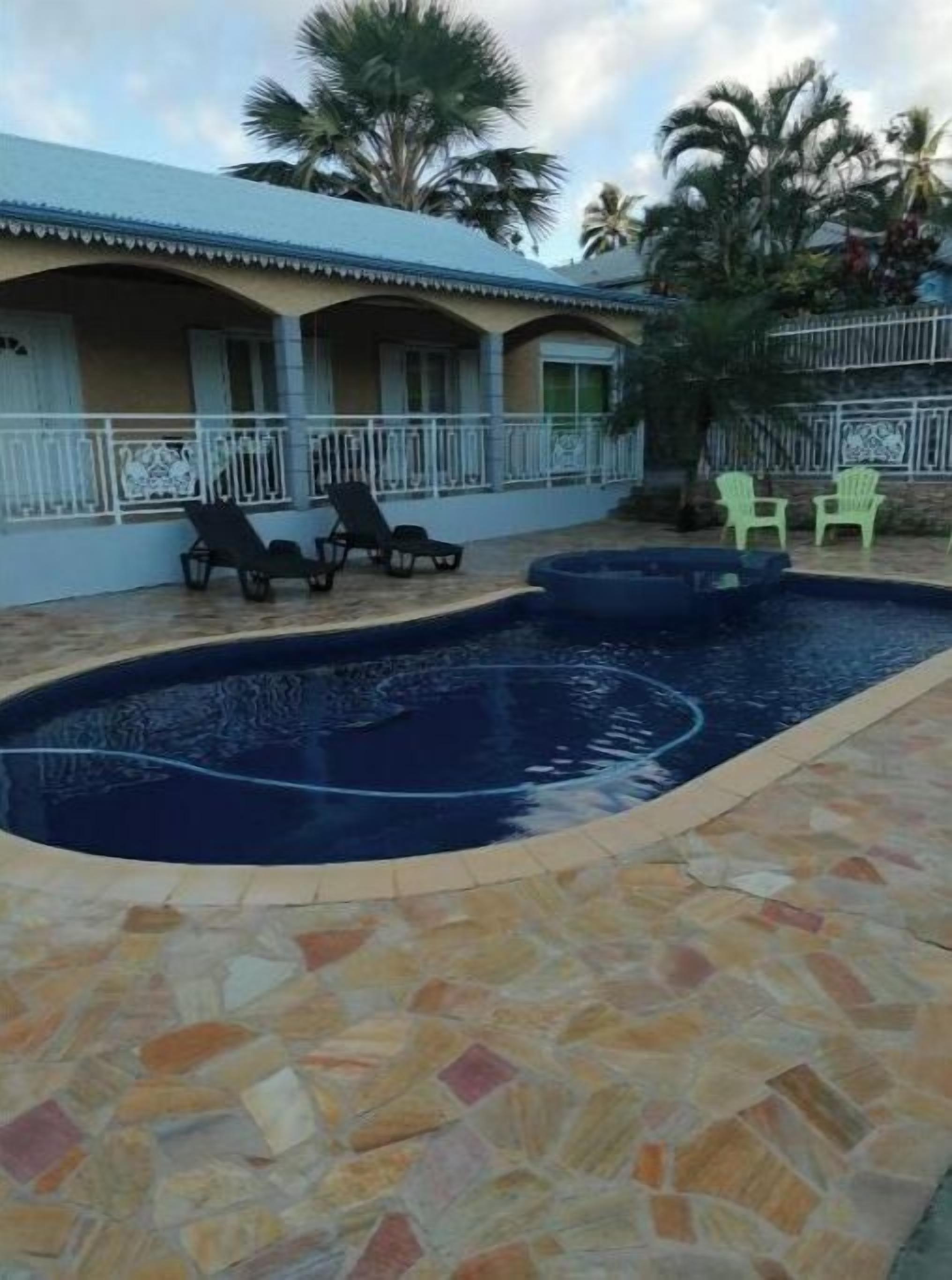 Uma piscina com espreguiçadeiras e um deck revestido de azulejos.