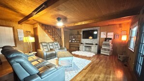 A cozy living room with a leather sofa, a TV, and a staircase. - Water view 3-bedroom house in Camden with AC and WiFi walking distance to lake (Camden)