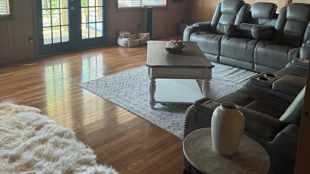A spacious living room with a wooden floor, a leather sofa, a coffee table, and a fluffy rug. - Water view 3-bedroom house in Camden with AC and WiFi walking distance to lake (Camden)