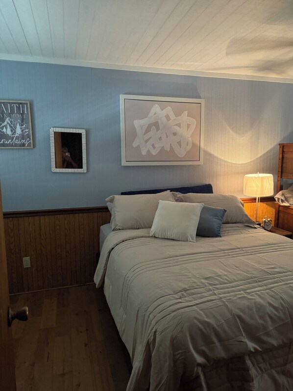 Un dormitorio con cama, mesita de noche, lámpara y adornos en la pared.