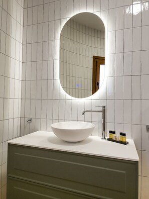 Bathroom features a large mirror, white sink, and green vanity with two drawers.