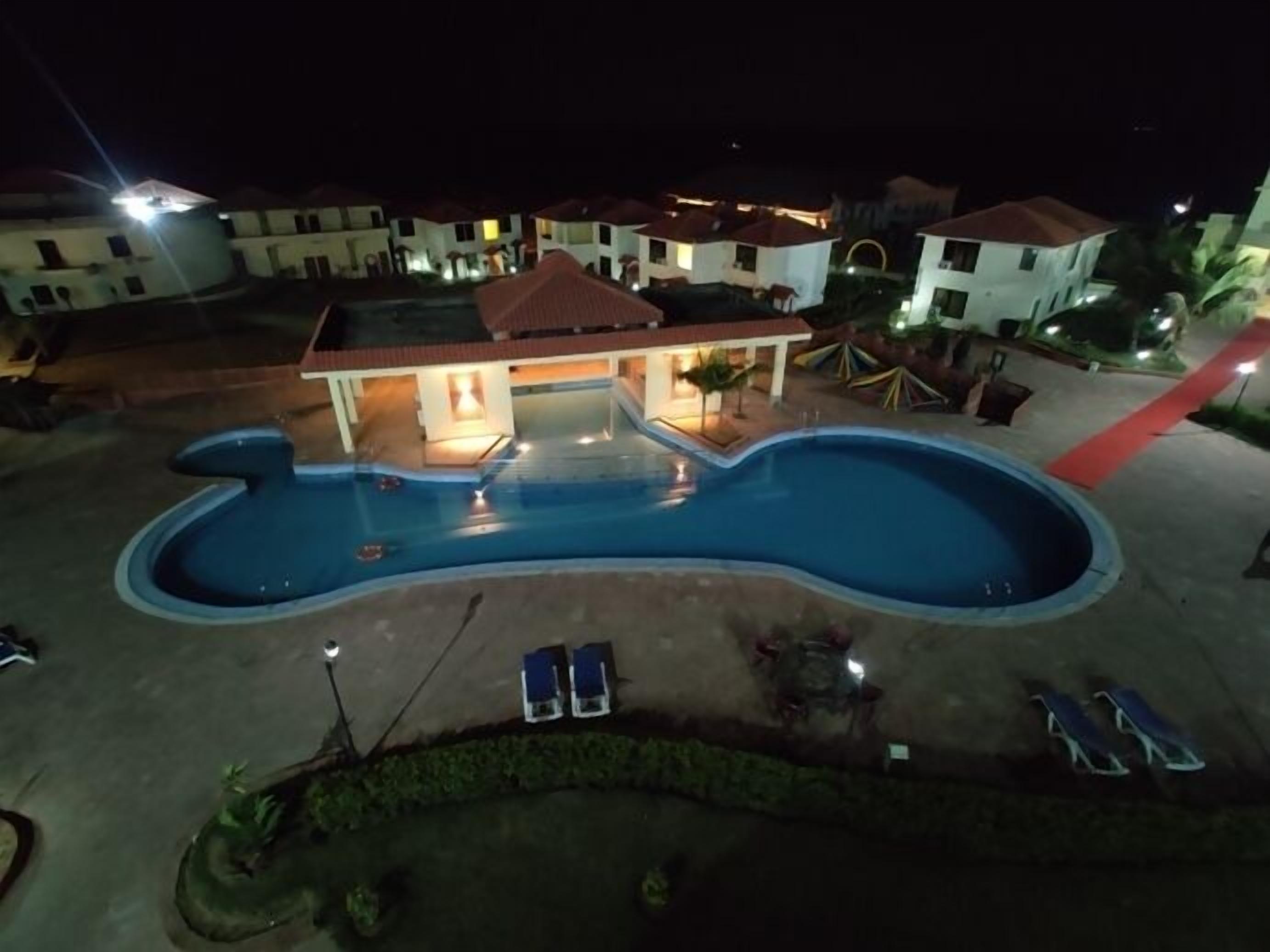 Una piscina d'una forma singular, envoltada de gandules i un edifici amb nombroses balconades.