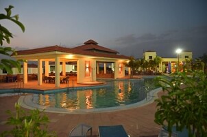 Una piscina al aire libre, sombrillas, sillones reclinables de piscina