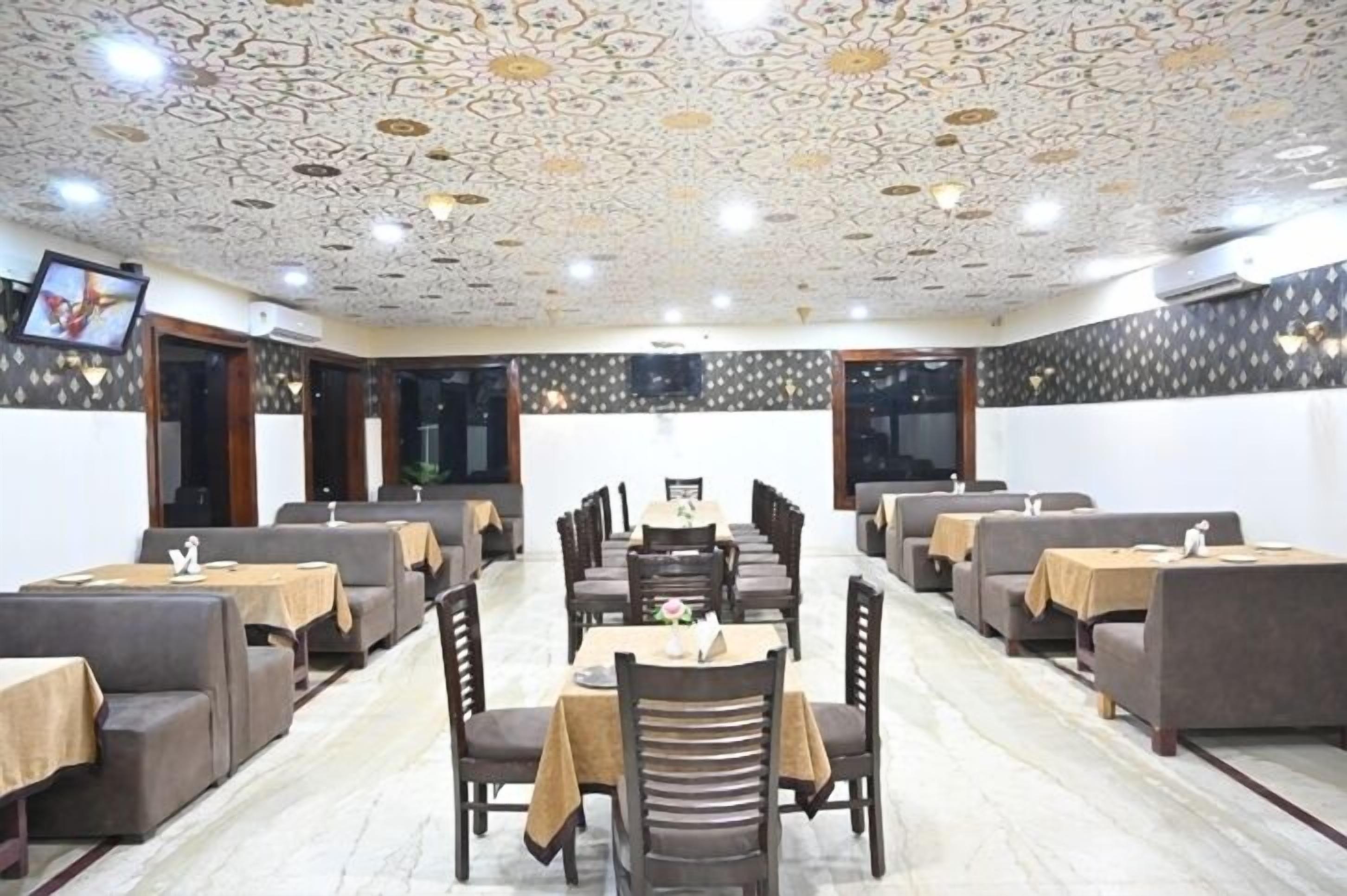 Un restaurante con techo estampado, varias mesas y cabinas para comer, y una pantalla de televisión en la pared.