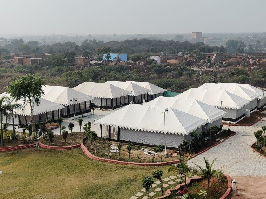 A series of white tents with a uniform design, arranged in a row with a paved walkway in between.
