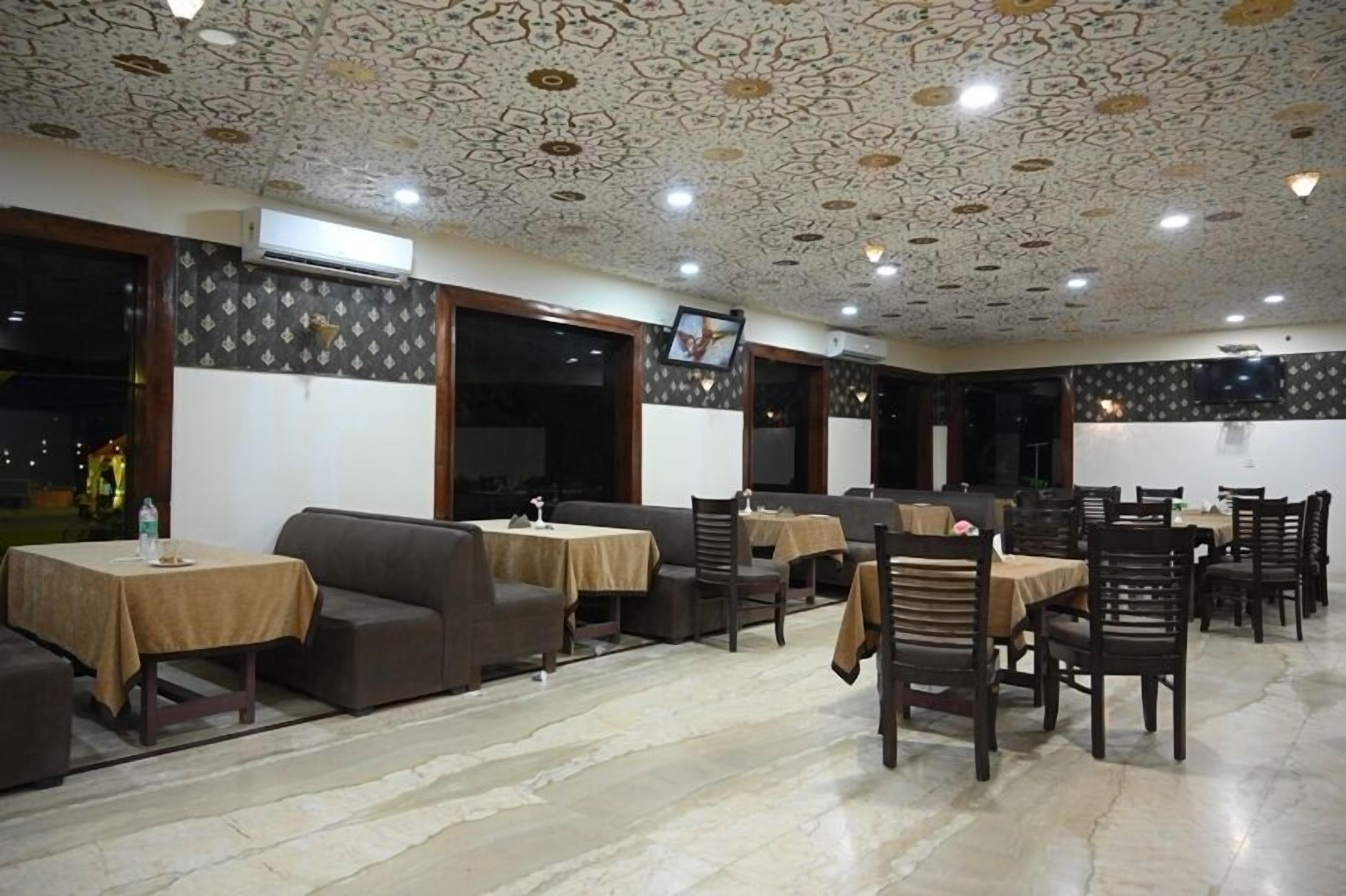 A restaurant with a patterned ceiling, multiple tables with chairs, and a tiled floor.