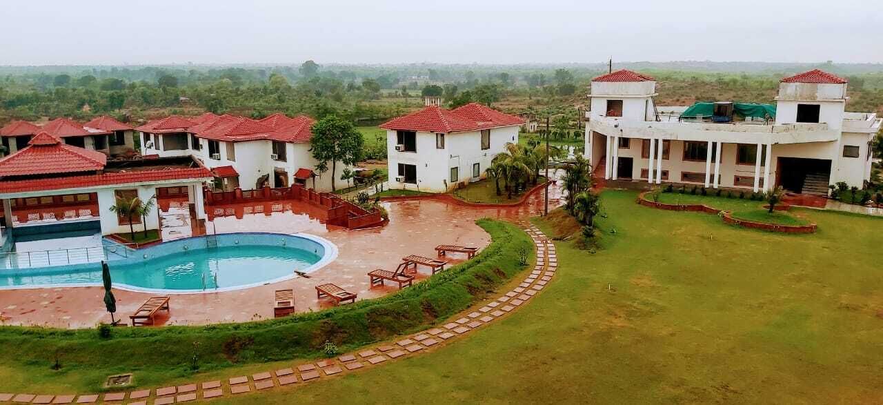 A resort with a swimming pool, multiple buildings with red-tiled roofs, and a well-maintained lawn.