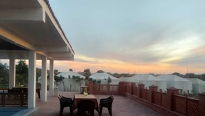 Una terraza con una mesa y sillas, con vistas a una hilera de tiendas de campaña.