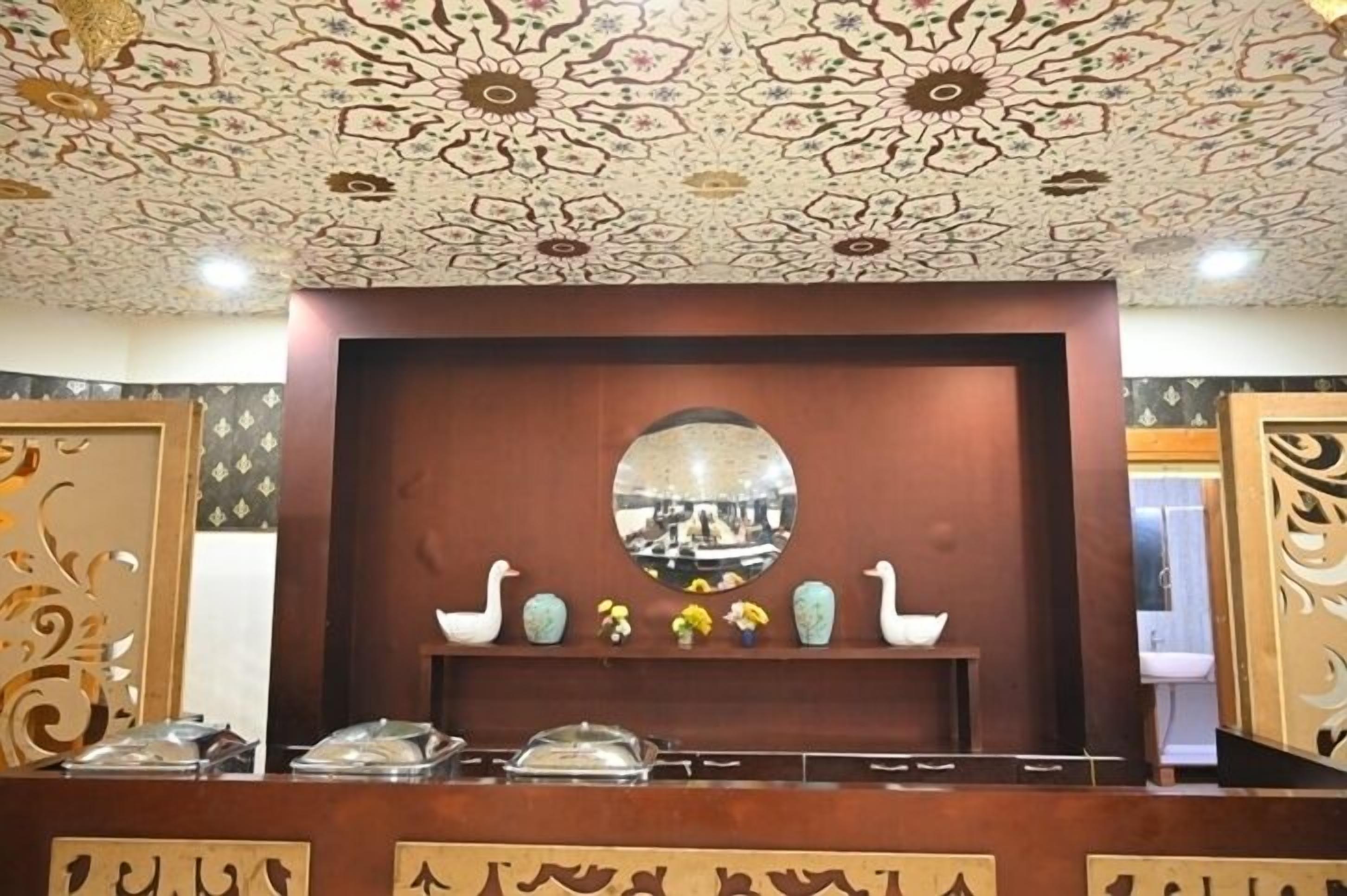 Un espace d  ’accueil agrémenté d’un plafond décoratif, d’un miroir et d’une collection de vases et de cygnes.