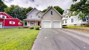 Ein zweigeschossiges Haus mit Garage, einer Veranda und einem gepflegten Rasen.
