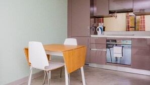 Kompakti keittiö, jossa on ruokapöytä ja -tuolit, sekä sisäänrakennettu uuni ja mikroaaltouuni.