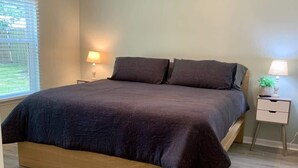 Una camera da letto con un letto, due comodini, una ventola a soffitto e una finestra con persiane.