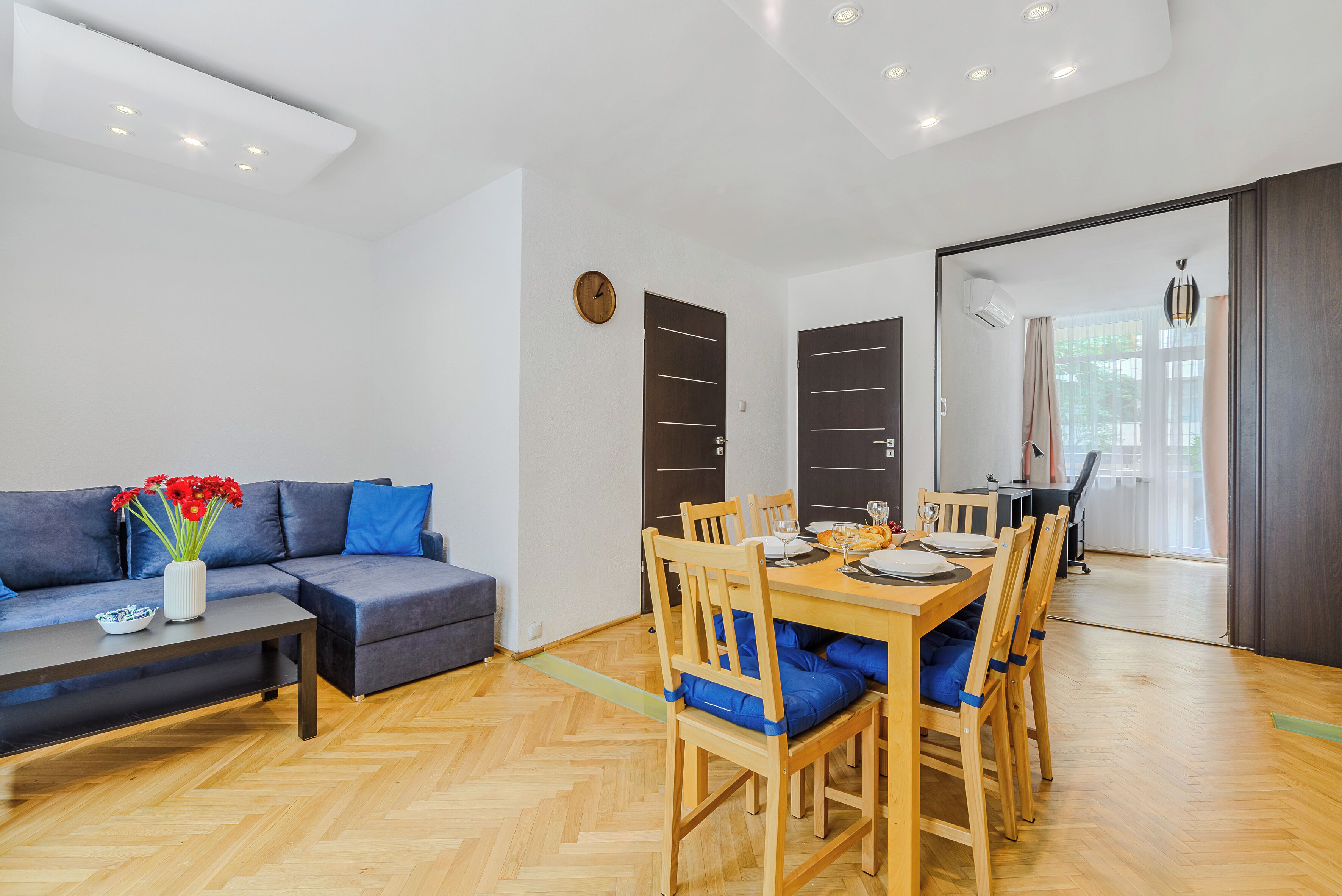 A modern living room with a sofa, coffee table, and dining table with chairs.