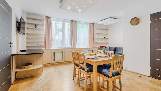 Une cuisine moderne avec un coin repas, des meubles en bois, une étagère intégrée et une fenêtre avec des rideaux.