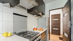 Une cuisine moderne équipée d’une cuisinière à gaz, d’appareils électroménagers en acier inoxydable et d’une variété de fruits et de légumes disposés sur le plan de travail.