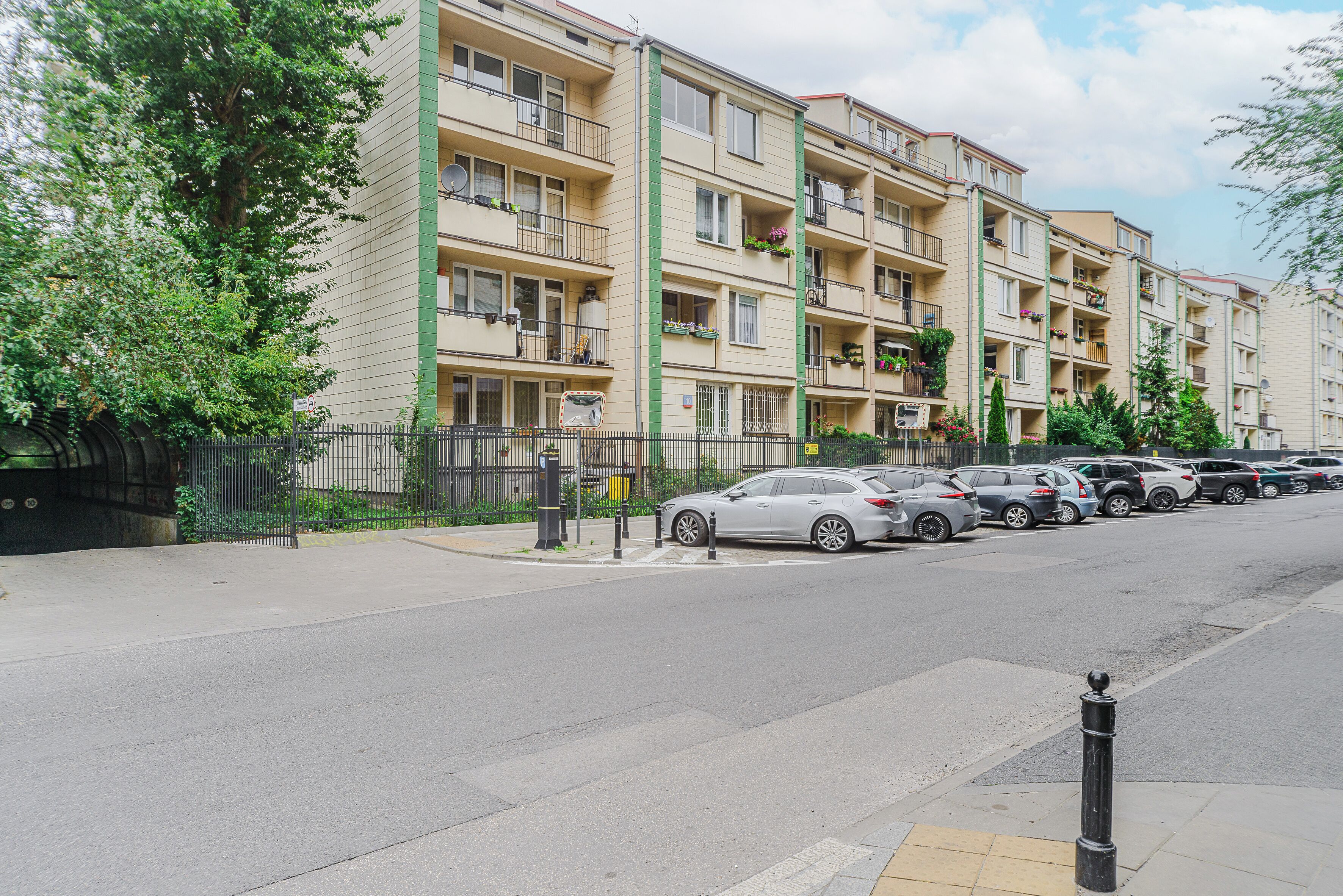 Um edifício residencial com vários andares, varandas, área de estacionamento e calçada.
