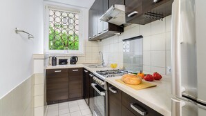 Une cuisine moderne avec des meubles en bois foncé, des appareils électroménagers en acier inoxydable et une fenêtre donnant sur un paysage verdoyant.