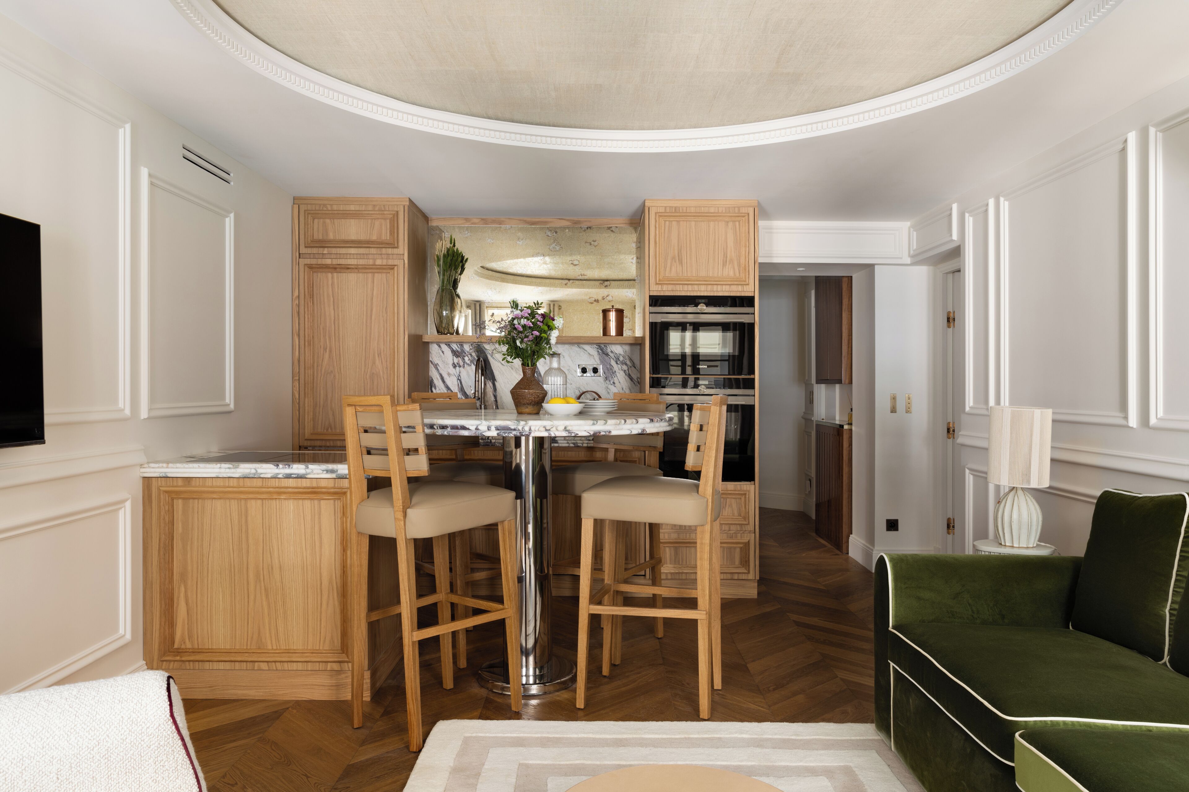 A modern kitchen with wooden cabinets, a marble countertop, and a central island with bar stools.