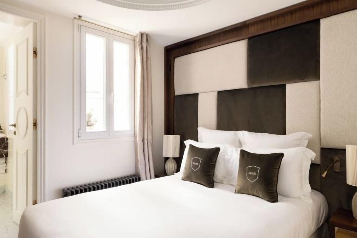 Ein Hotelzimmer mit einem großen Bett, einem hölzernen Kopfteil und zwei Nachttischlampen.