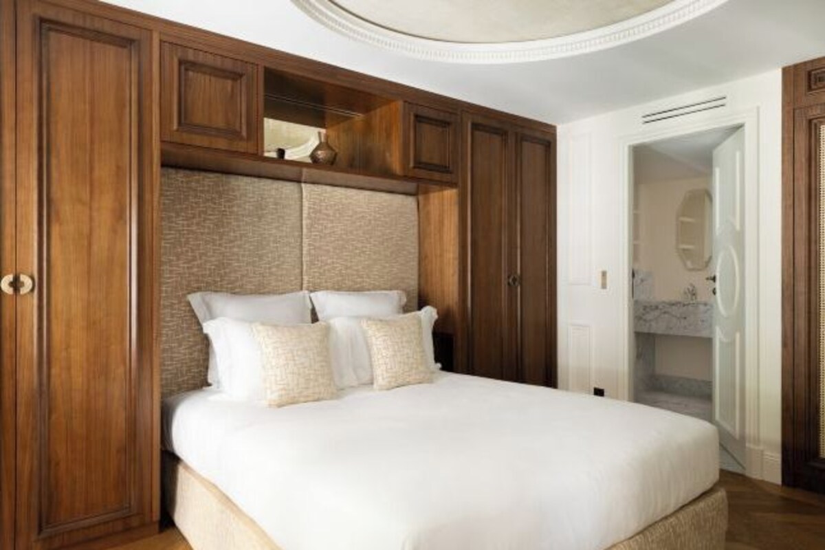 Une chambre avec un grand lit, une armoire en bois et une tête de lit intégrée.