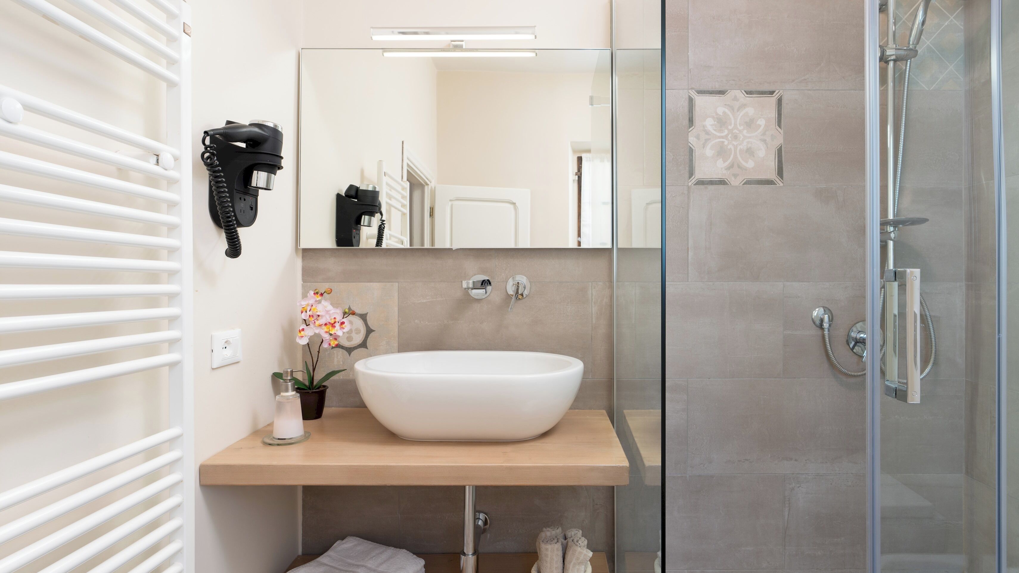 Ein Badezimmer mit einem weißen Waschbecken, einer Duschkabine aus Glas und einem Handtuchhalter.