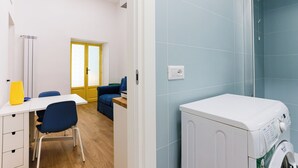 Une buanderie équipée d’un lave-linge, d’une table avec des chaises et d’une porte dont les panneaux sont en verre dépoli.