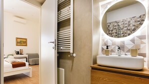 Ein modernes Badezimmer mit einem weißen Waschbecken, einer Holzausstattung und einer Rückwand aus geometrischen Fliesen.