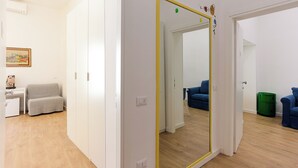Eine moderne Wohnung mit einem großen Spiegel, Holzboden, einem grauen Sofa und einem kleinen Tisch mit einer Lampe.