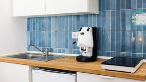 Una cocina con cafetera, lavavajillas y una tablet sobre la encimera.