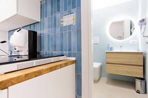 Une salle de bain moderne avec des carreaux bleus, un meuble-lavabo en bois, un lavabo avec un miroir et un sèche-cheveux fixé au mur.