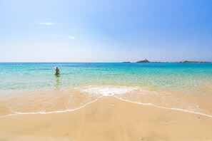 A beach with clear turquoise water, a sandy shore, and a person in the water. - Donna Giovanna Holiday Home Pula (Pula)
