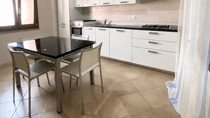A kitchen with white cabinets, a black countertop, and a dining table with chairs. - Donna Giovanna Holiday Home Pula (Pula)