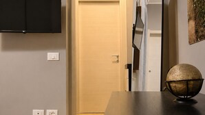 A modern interior with a flat-screen TV mounted on the wall, a wooden dining table, and a door leading to another room. - Donna Giovanna Holiday Home Pula (Pula)