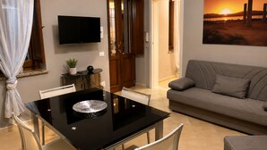 A modern living room with a dining table, sofa, TV, and a painting of a sunset. - Donna Giovanna Holiday Home Pula (Pula)