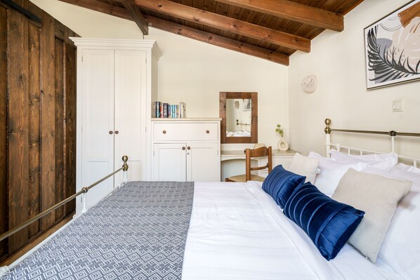 Un dormitorio con cama, armario, escritorio y silla.
