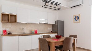 A modern kitchen with white cabinets, a wooden countertop, and a dining table with chairs. - Russu Suli Apartment 2 by Wonderful Italy (Siracusa)