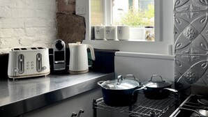 A kitchen with a toaster, a kettle, a coffee maker, and pots on the counter.