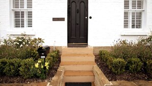 A white building with a black door, a mailbox, and a small sign above the door.