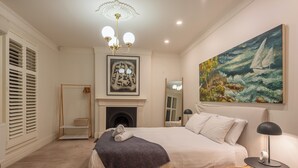 Un dormitorio con cama, un cuadro, chimenea y candelabro.