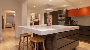 Una cocina moderna con una isla grande, electrodomésticos de acero inoxidable y taburetes de bar de madera.