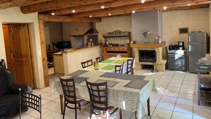 Une cuisine chaleureuse avec des poutres en bois, une table à manger avec des chaises, un réfrigérateur et un four à micro-ondes.