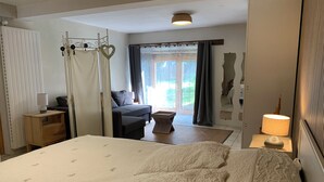 Une chambre dotée d’un grand lit, d’une table de chevet avec une lampe, d’une armoire, d’un coin salon avec un canapé et offrant une vue sur l’extérieur par une fenêtre.
