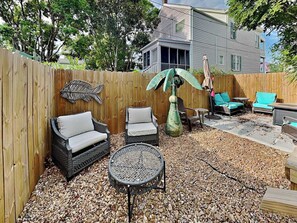 A backyard with a wooden fence, outdoor furniture, and a decorative fish sculpture.