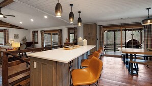 Una cocina amplia con una isla central, piso de madera e iluminación colgante.