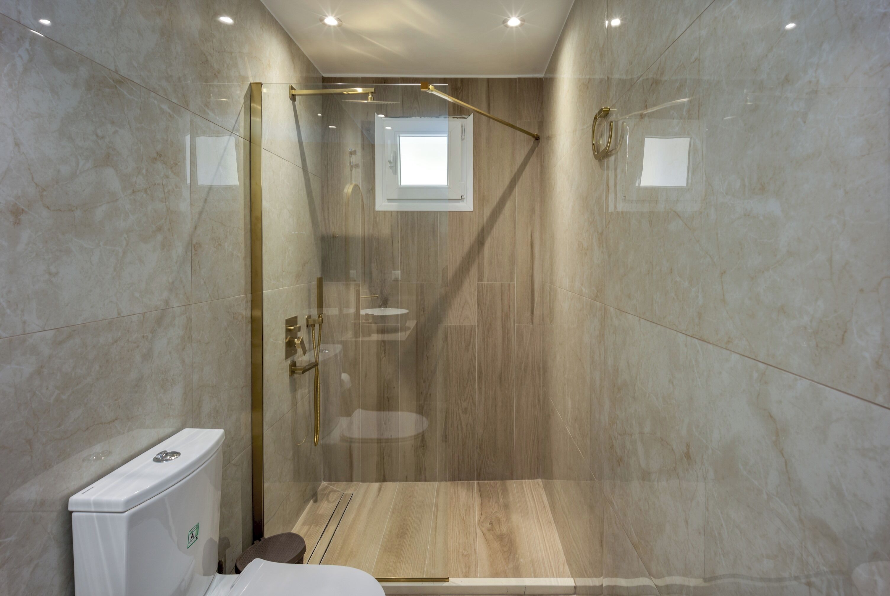 Une salle de bain moderne avec une douche à parois de verre, des murs en marbre et des toilettes.