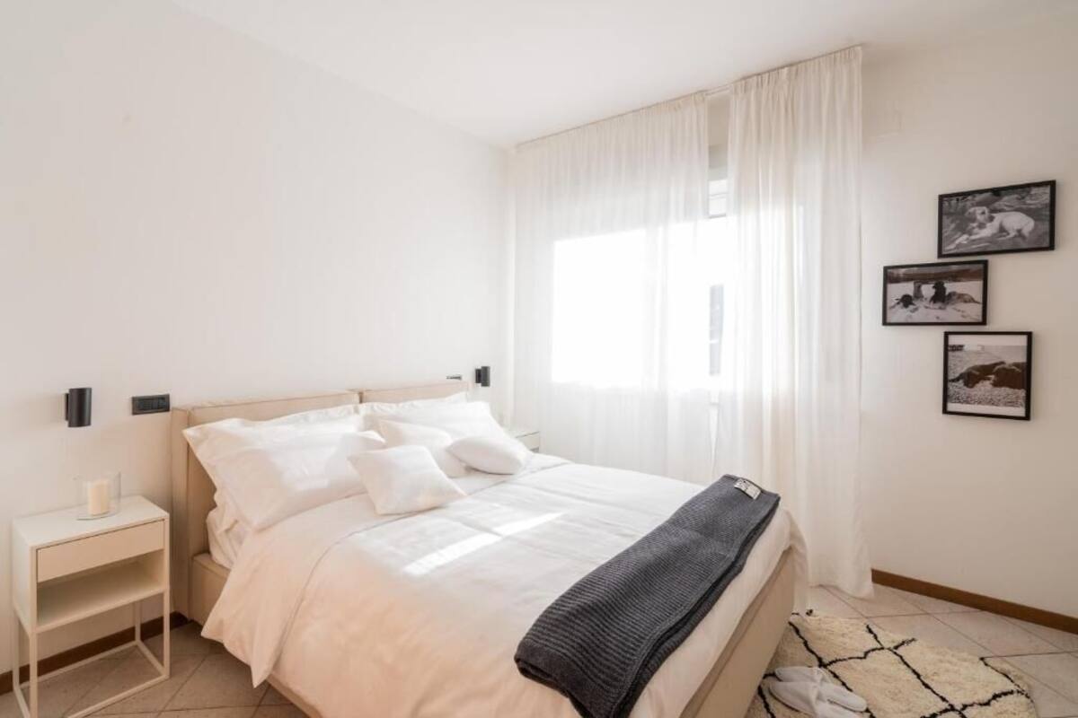 Een slaapkamer met een bed, een nachtkastje en een raam met gordijnen.