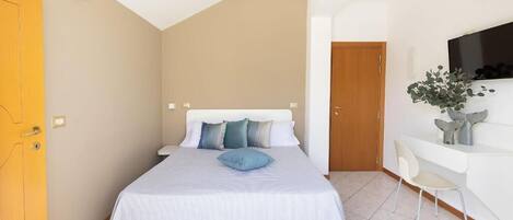Un dormitorio con cama, escritorio y televisión.